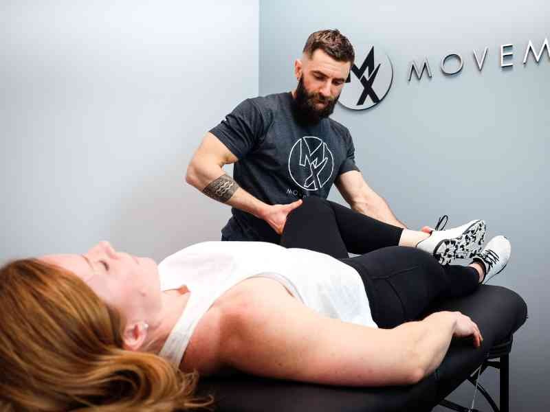 Stretch therapist guiding a client through an assisted leg stretch on a treatment table